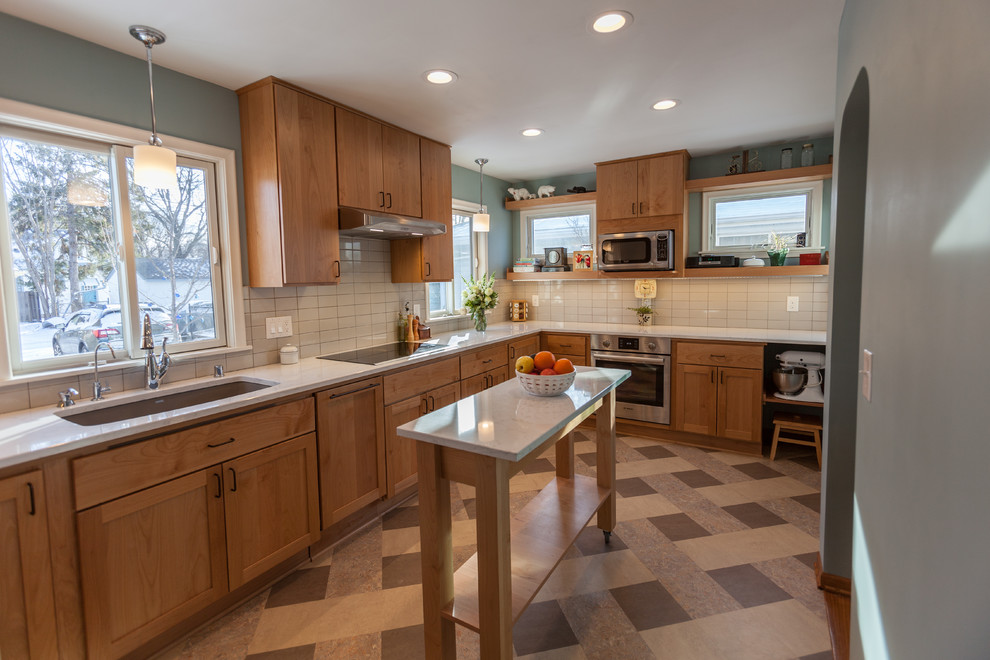 Foto på ett avskilt, mellanstort minimalistiskt vit u-kök, med en undermonterad diskho, släta luckor, skåp i ljust trä, bänkskiva i kvarts, vitt stänkskydd, stänkskydd i keramik, rostfria vitvaror, linoleumgolv, en köksö och flerfärgat golv