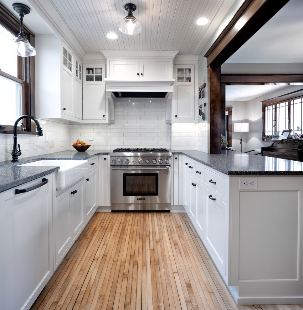 Foto på ett mellanstort vintage grå kök, med en rustik diskho, skåp i shakerstil, vita skåp, bänkskiva i återvunnet glas, vitt stänkskydd, stänkskydd i tunnelbanekakel, integrerade vitvaror, ljust trägolv, en halv köksö och brunt golv