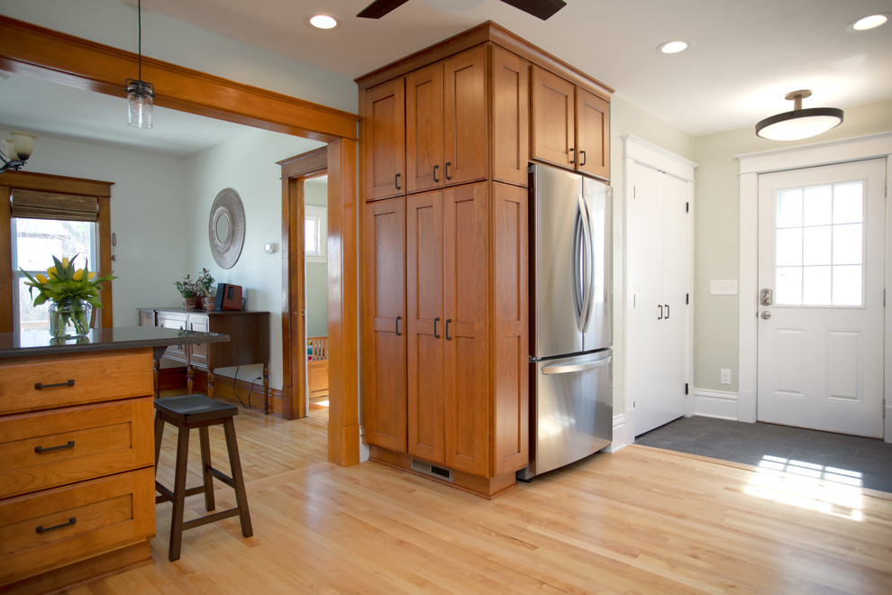 Foto på ett mellanstort amerikanskt grå kök, med en undermonterad diskho, luckor med infälld panel, skåp i mellenmörkt trä, bänkskiva i kvarts, vitt stänkskydd, stänkskydd i keramik, rostfria vitvaror, ljust trägolv, en halv köksö och brunt golv