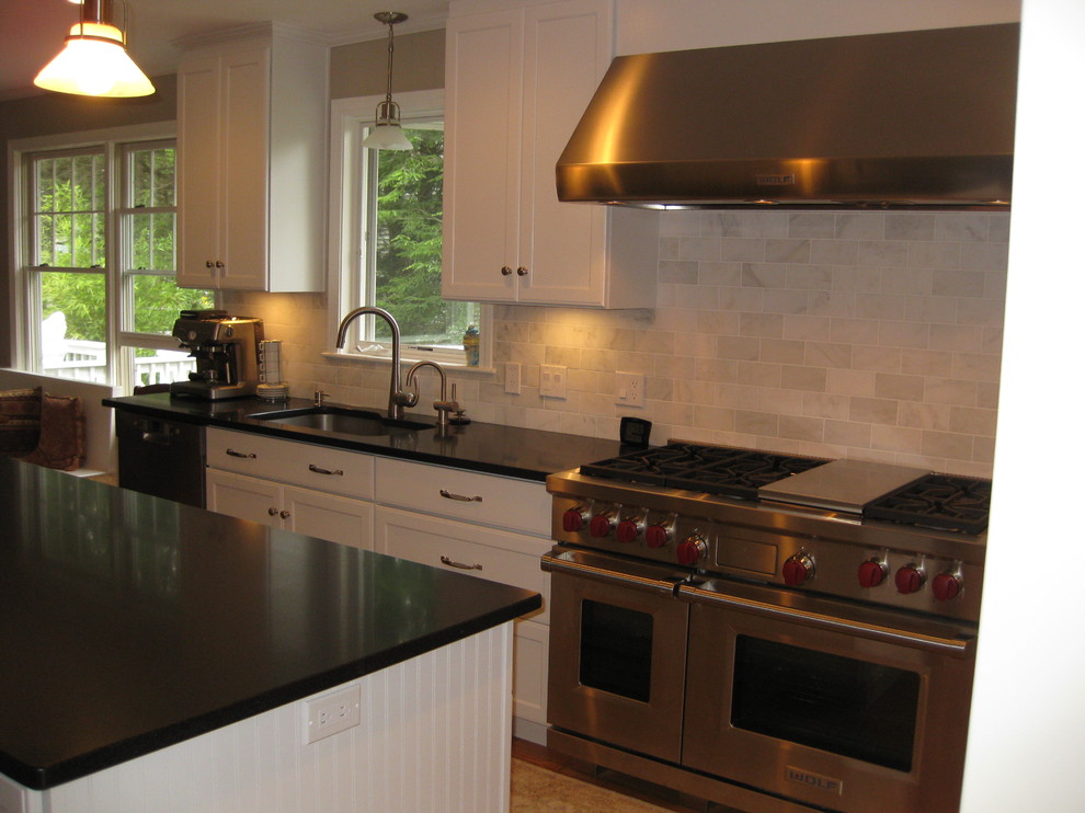 Example of a transitional u-shaped medium tone wood floor eat-in kitchen design in Boston with an undermount sink, recessed-panel cabinets, white cabinets, gray backsplash, subway tile backsplash, stainless steel appliances, an island and black countertops