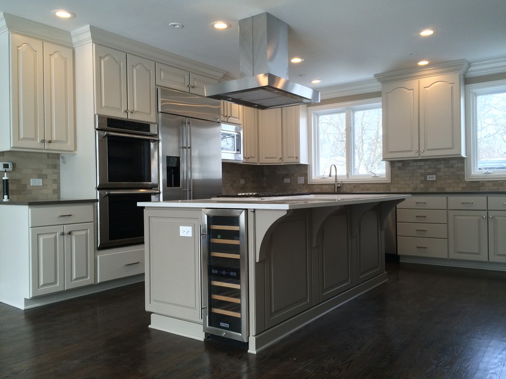 Enclosed kitchen - large traditional l-shaped dark wood floor and brown floor enclosed kitchen idea in Chicago with an undermount sink, raised-panel cabinets, white cabinets, solid surface countertops, beige backsplash, stone tile backsplash, stainless steel appliances and an island