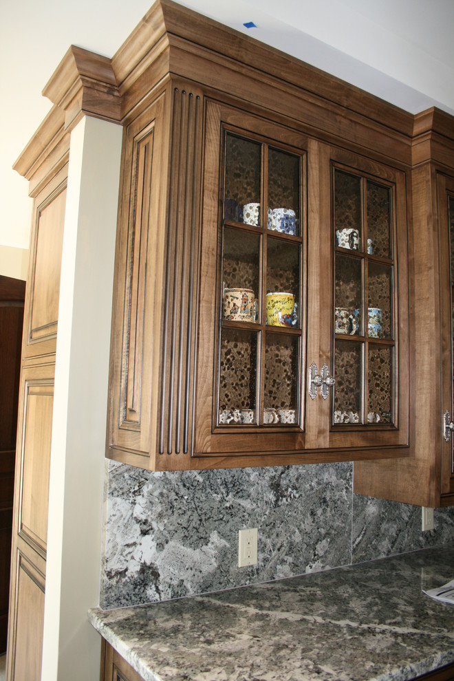 Cette image montre une cuisine méditerranéenne avec un placard à porte affleurante, des portes de placard beiges, un plan de travail en granite, un électroménager en acier inoxydable et parquet foncé.