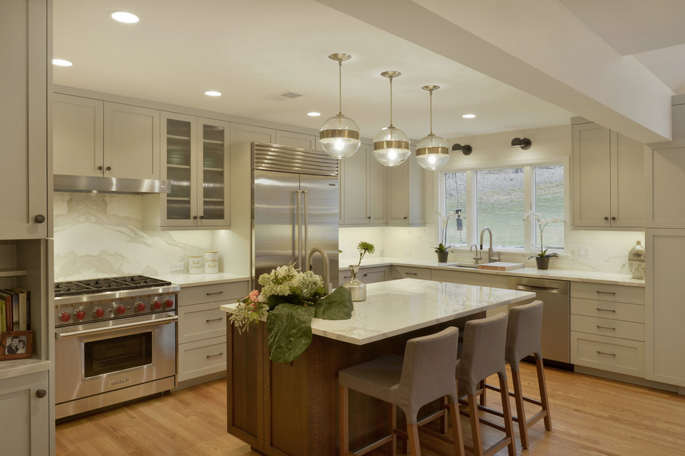 Example of a mid-sized minimalist u-shaped light wood floor and brown floor eat-in kitchen design in New York with an undermount sink, shaker cabinets, gray cabinets, tile countertops, white backsplash, porcelain backsplash, stainless steel appliances and an island