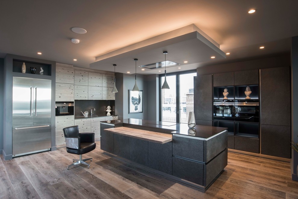 Moderne Küche in L-Form mit flächenbündigen Schrankfronten, grauen Schränken, Küchenrückwand in Grau, Küchengeräten aus Edelstahl, dunklem Holzboden, Kücheninsel, braunem Boden und schwarzer Arbeitsplatte in West Midlands