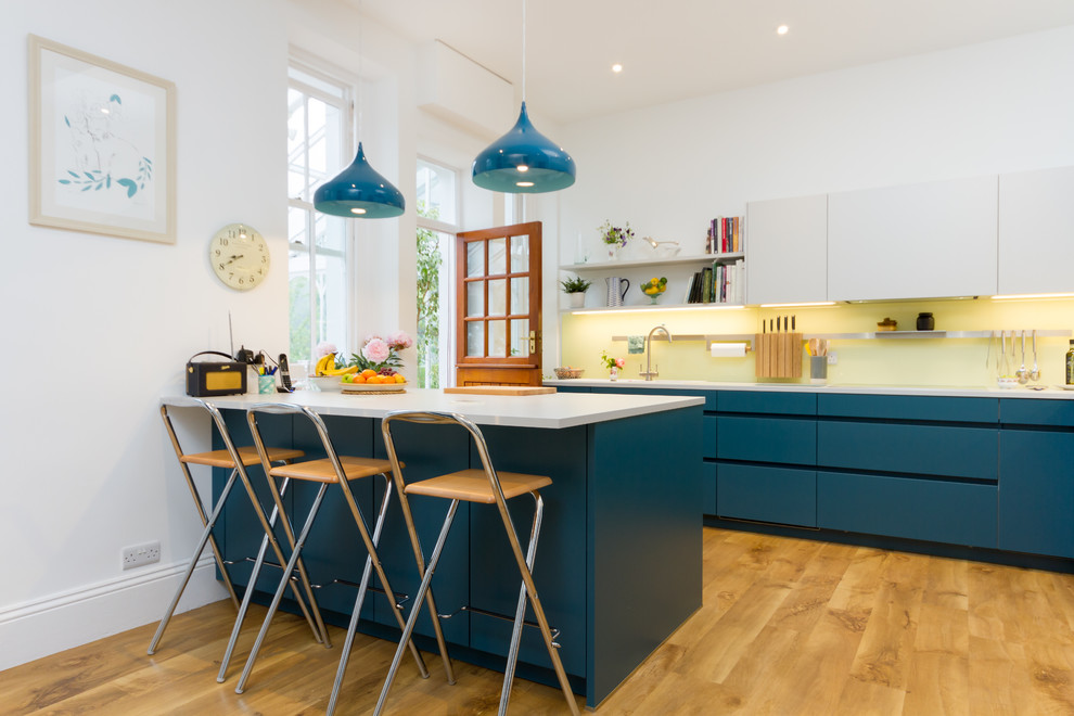 Esempio di una cucina lineare minimal di medie dimensioni con ante lisce, ante blu, top in quarzite, parquet chiaro, penisola, pavimento beige e top bianco