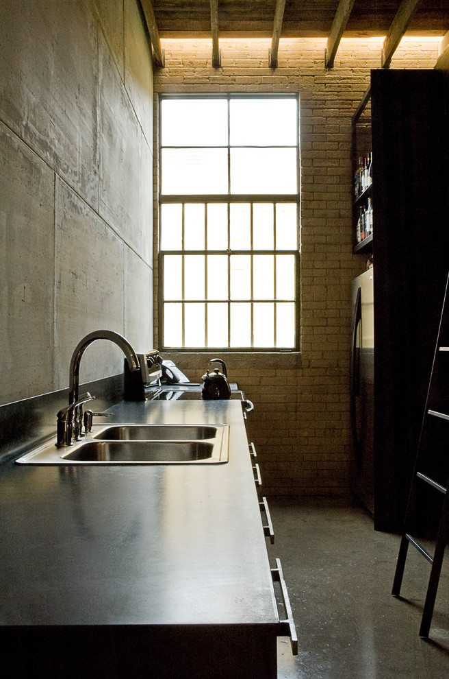 Cette image montre une cuisine design avec un évier 2 bacs, une crédence grise, une crédence en carreau de ciment, un électroménager en acier inoxydable et sol en béton ciré.