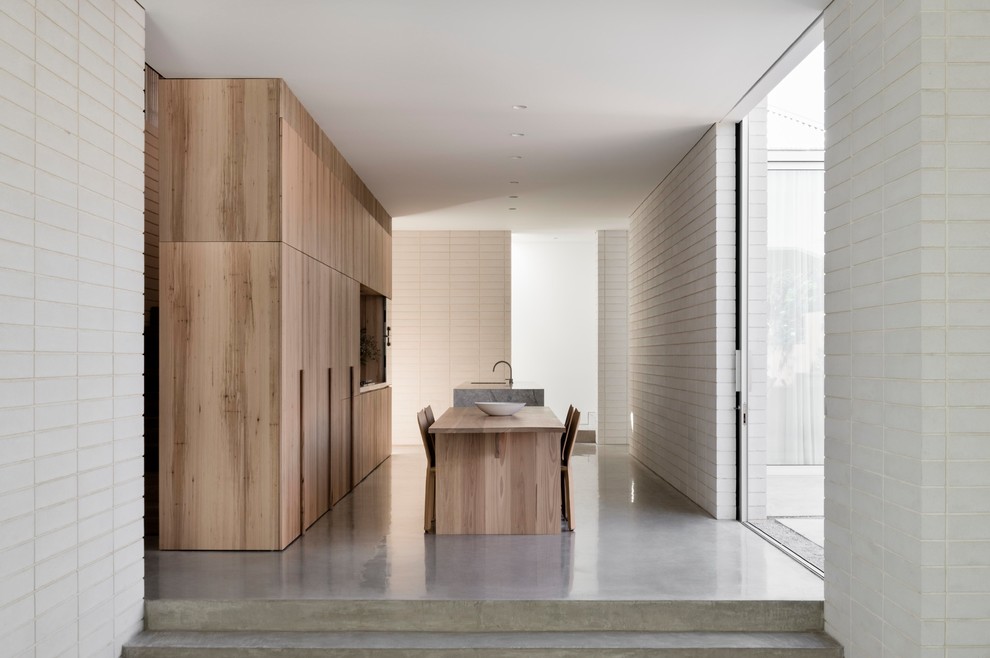 Источник вдохновения для домашнего уюта: кухня в стиле модернизм с обеденным столом, плоскими фасадами, светлыми деревянными фасадами, бетонным полом, островом и серым полом