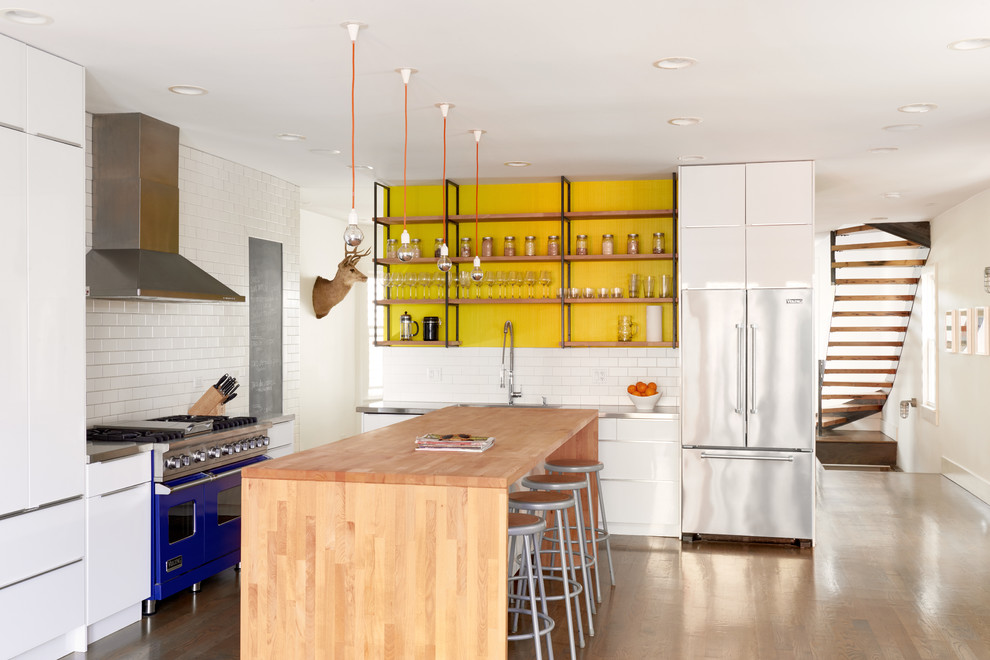 Foto på ett mellanstort funkis kök, med öppna hyllor, bänkskiva i rostfritt stål, vitt stänkskydd, stänkskydd i tunnelbanekakel, färgglada vitvaror, ljust trägolv, en köksö, en integrerad diskho och vita skåp