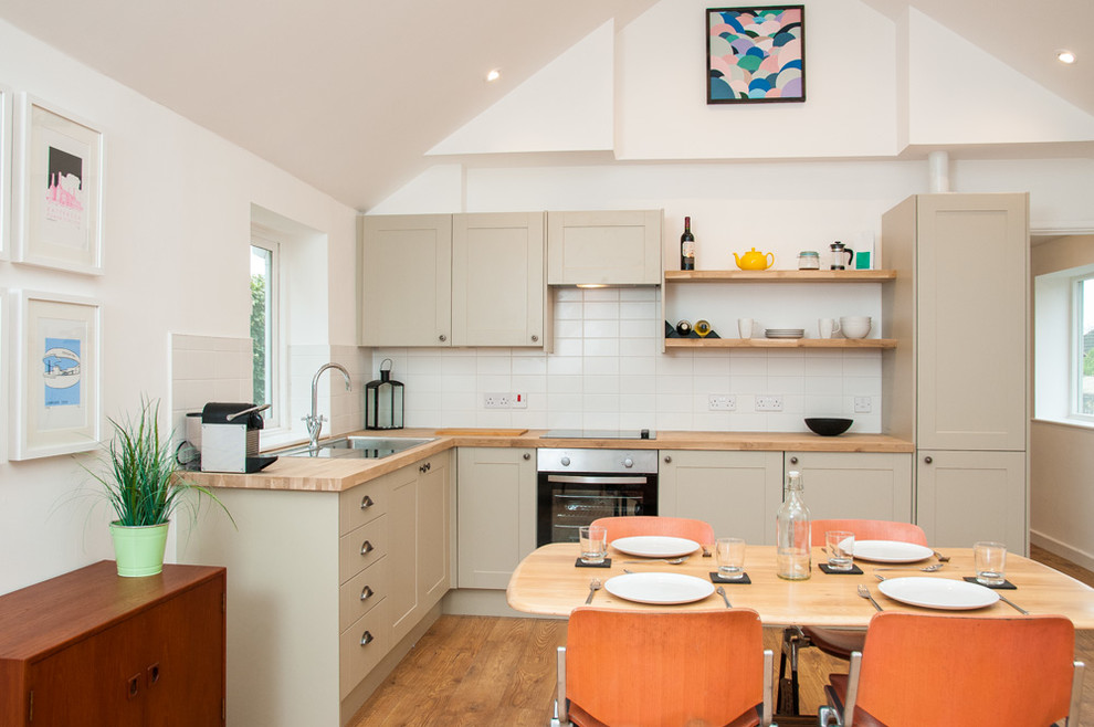 Moderne Wohnküche in L-Form mit Einbauwaschbecken, Schrankfronten im Shaker-Stil, beigen Schränken, Arbeitsplatte aus Holz, Küchenrückwand in Weiß, braunem Holzboden, braunem Boden und brauner Arbeitsplatte in Wiltshire