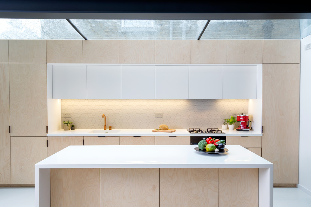 Inredning av ett modernt avskilt, litet linjärt kök, med en integrerad diskho, släta luckor, skåp i ljust trä, stänkskydd i keramik, svarta vitvaror, betonggolv, en köksö och turkost golv