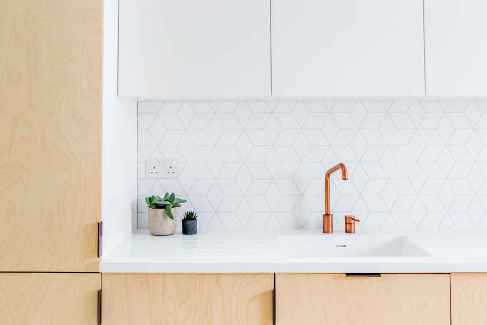 Idee per una piccola cucina moderna con lavello integrato, ante lisce, ante in legno chiaro, paraspruzzi bianco, paraspruzzi con piastrelle in ceramica, elettrodomestici neri, pavimento in cemento e pavimento bianco