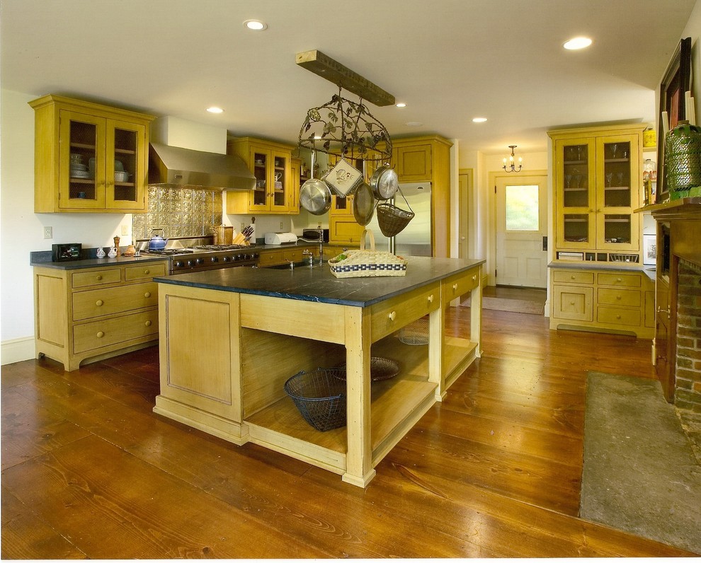 Example of a large country medium tone wood floor kitchen design in New York with a farmhouse sink, recessed-panel cabinets, distressed cabinets and soapstone countertops