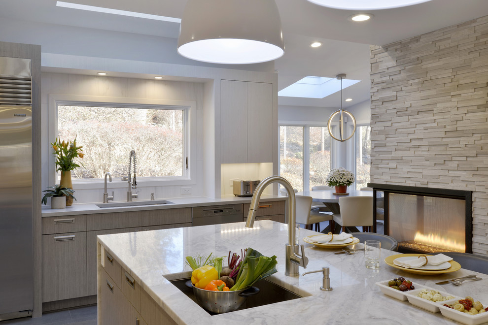 Open concept kitchen - large modern l-shaped limestone floor open concept kitchen idea in New York with an undermount sink, flat-panel cabinets, white cabinets, quartzite countertops, white backsplash, stone tile backsplash, stainless steel appliances and an island