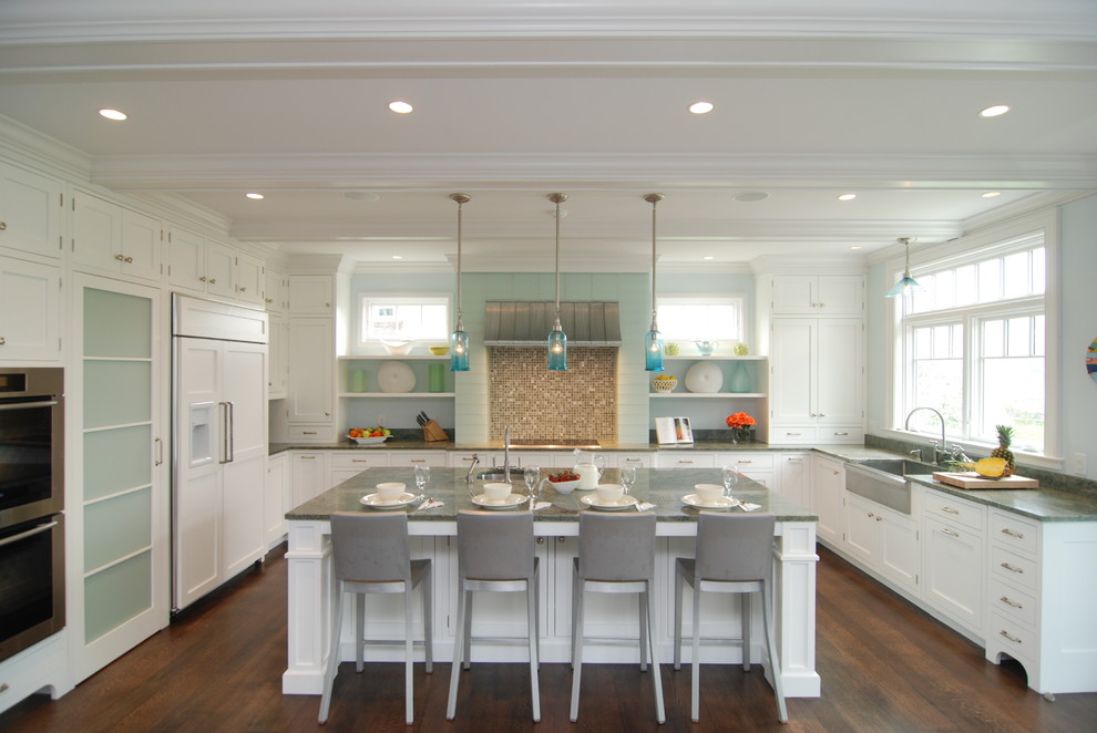 Example of a large classic u-shaped medium tone wood floor eat-in kitchen design in New York with a farmhouse sink, shaker cabinets, white cabinets, granite countertops, blue backsplash, glass tile backsplash, white appliances and an island