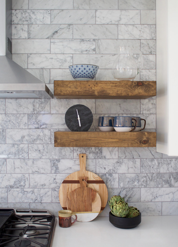 Bild på ett lantligt kök, med en undermonterad diskho, skåp i shakerstil, vita skåp, bänkskiva i kvarts, grått stänkskydd, stänkskydd i marmor, rostfria vitvaror, laminatgolv, en köksö och brunt golv