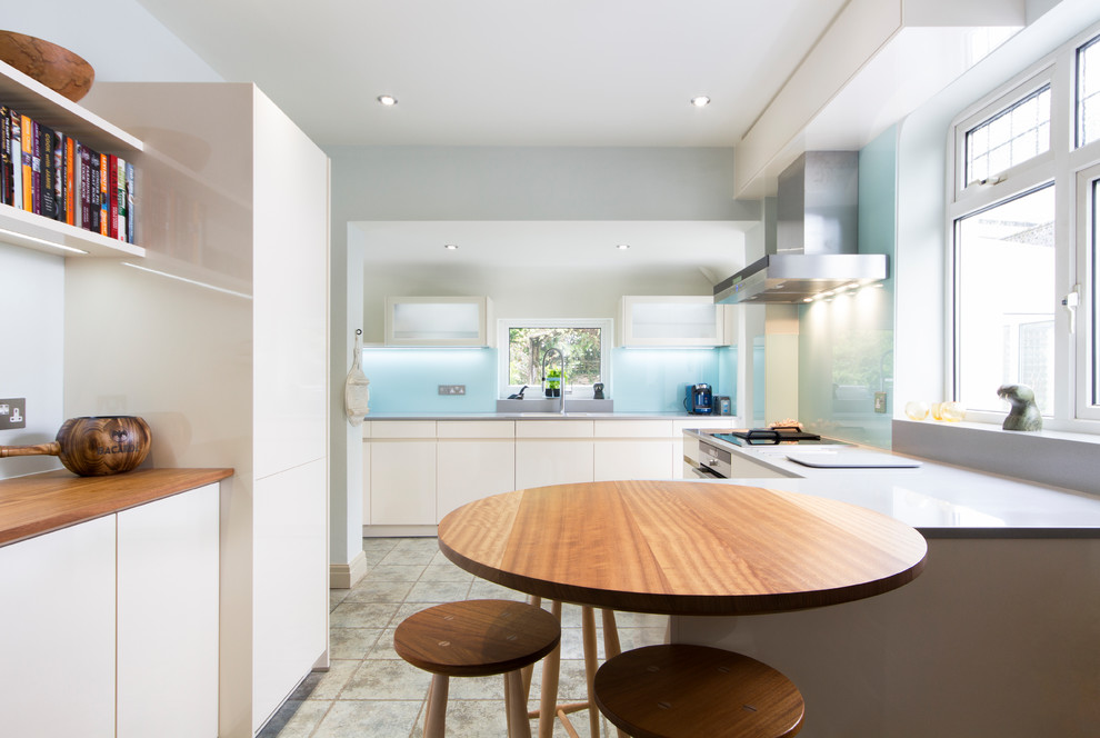 Große Moderne Küche mit flächenbündigen Schrankfronten, weißen Schränken, Halbinsel und grauem Boden in Devon