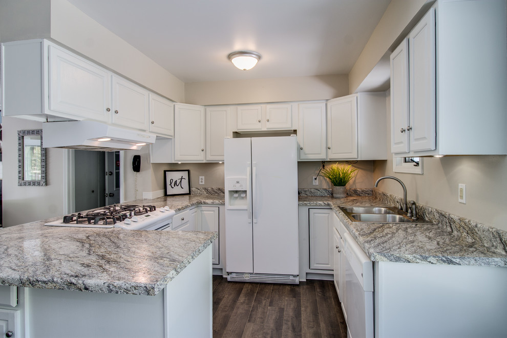 This is an example of a bohemian kitchen in Grand Rapids with a built-in sink, raised-panel cabinets, white cabinets, laminate countertops, white appliances, laminate floors, brown floors and multicoloured worktops.