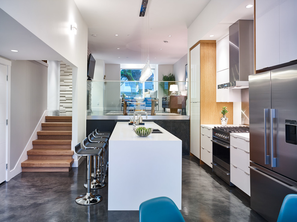 Photo of a medium sized contemporary galley kitchen/diner in Vancouver with a submerged sink, flat-panel cabinets, white cabinets, engineered stone countertops, white splashback, glass sheet splashback, stainless steel appliances, concrete flooring and an island.