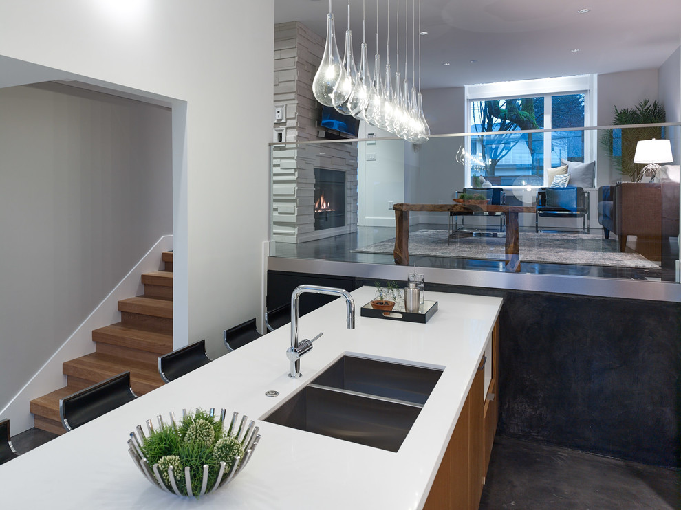 Photo of a medium sized contemporary galley kitchen/diner in Vancouver with a submerged sink, flat-panel cabinets, white cabinets, engineered stone countertops, white splashback, glass sheet splashback, stainless steel appliances, concrete flooring and an island.