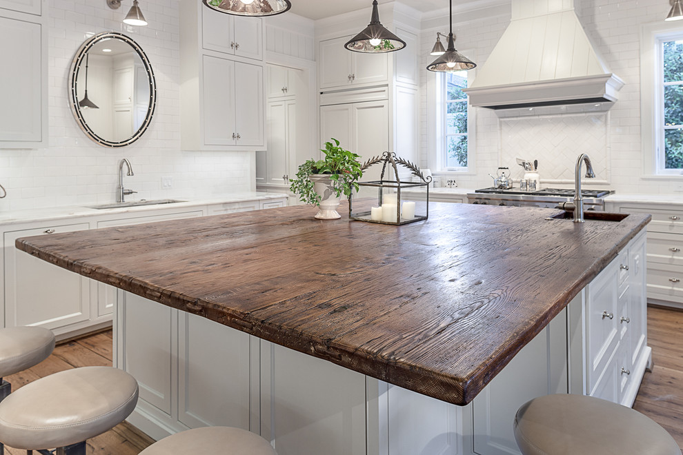 This is an example of a traditional kitchen in Houston with recessed-panel cabinets, white cabinets, wood worktops, white splashback, metro tiled splashback and stainless steel appliances.