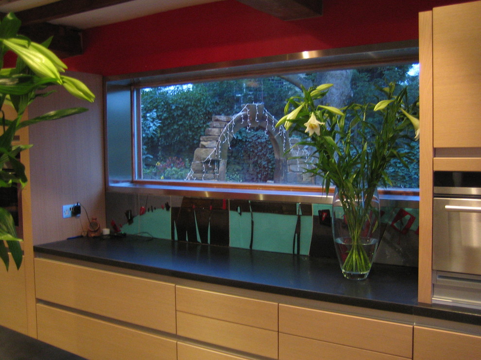 Immagine di una cucina classica di medie dimensioni con lavello sottopiano, ante lisce, ante in legno chiaro, top in granito, paraspruzzi nero, paraspruzzi con lastra di vetro, elettrodomestici in acciaio inossidabile e pavimento in ardesia