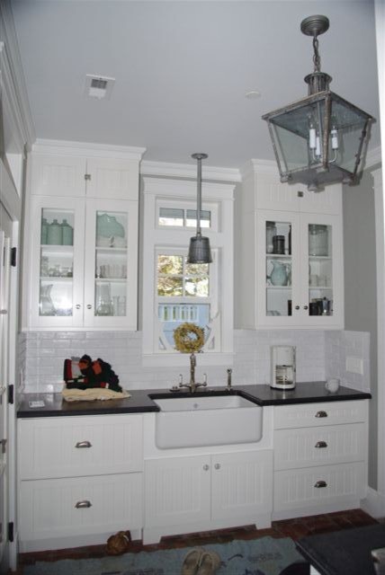 Foto på ett mellanstort lantligt kök, med en rustik diskho, skåp i shakerstil, vita skåp, bänkskiva i täljsten, vitt stänkskydd, stänkskydd i tunnelbanekakel och tegelgolv