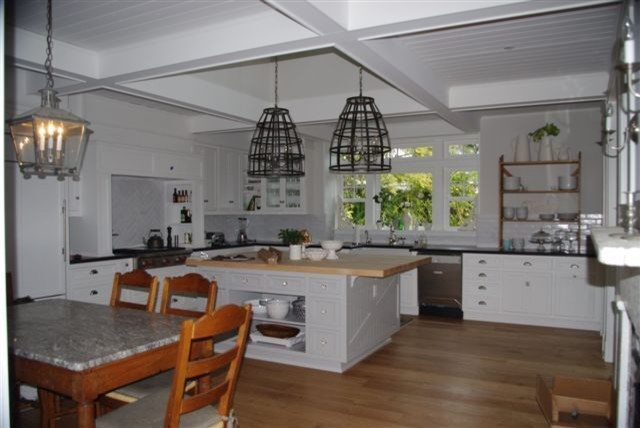 This is an example of a medium sized farmhouse l-shaped kitchen/diner in San Diego with a belfast sink, shaker cabinets, white cabinets, soapstone worktops, white splashback, metro tiled splashback, brick flooring and an island.