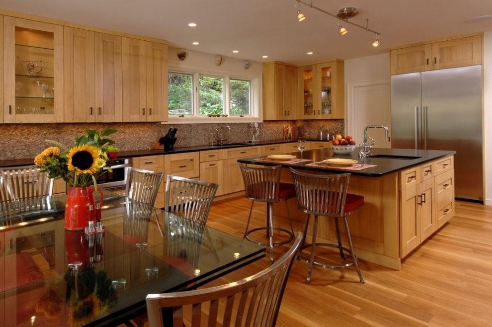 Example of a trendy l-shaped eat-in kitchen design in DC Metro with an undermount sink, shaker cabinets, light wood cabinets, granite countertops, multicolored backsplash and stainless steel appliances