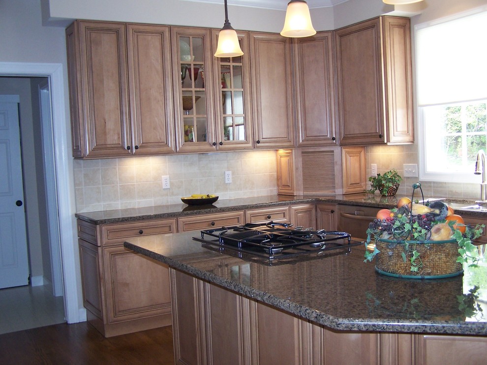 Medium sized traditional l-shaped kitchen in St Louis with a double-bowl sink, raised-panel cabinets, light wood cabinets, granite worktops, beige splashback, ceramic splashback, medium hardwood flooring, an island and brown floors.