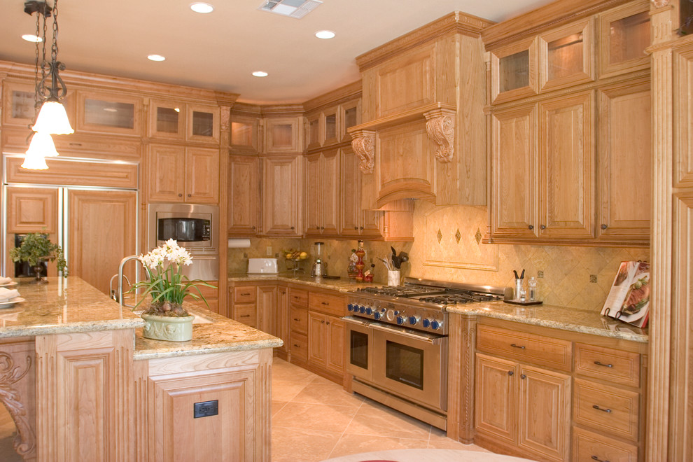 Exempel på ett mellanstort klassiskt kök, med en undermonterad diskho, luckor med upphöjd panel, skåp i ljust trä, granitbänkskiva, beige stänkskydd, stänkskydd i stenkakel, integrerade vitvaror, kalkstensgolv och en köksö