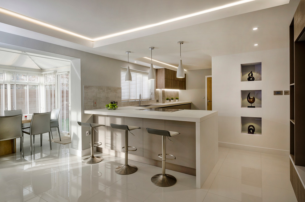 This is an example of a large modern l-shaped kitchen in Devon with a double-bowl sink, flat-panel cabinets, laminate countertops, grey splashback, porcelain splashback, stainless steel appliances, porcelain flooring and a breakfast bar.