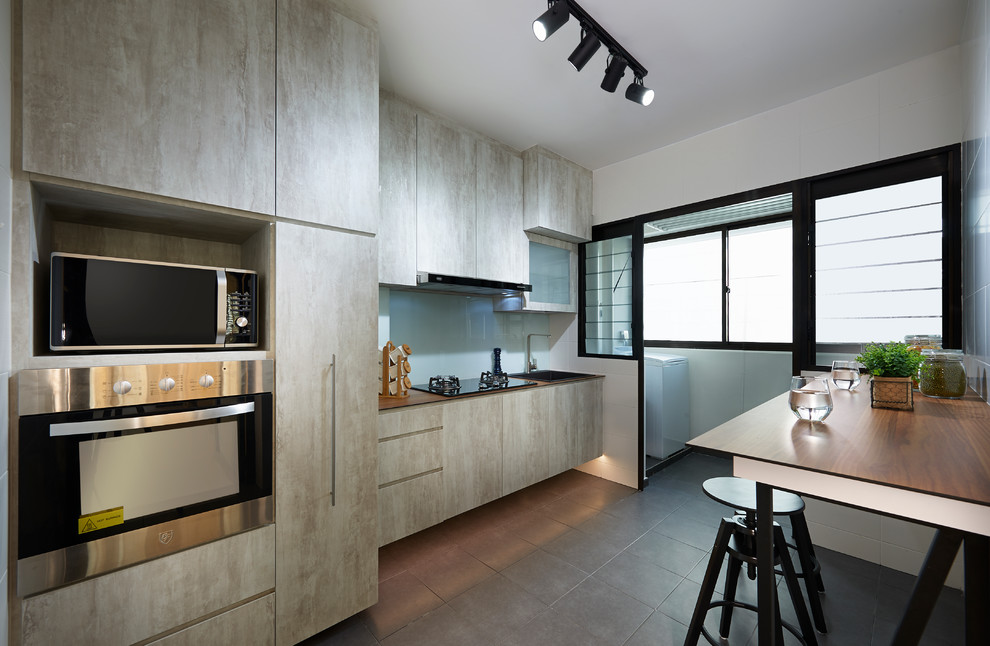 Danish single-wall ceramic tile kitchen photo in Singapore with a single-bowl sink, flat-panel cabinets, laminate countertops, white backsplash, glass sheet backsplash, black appliances and gray cabinets