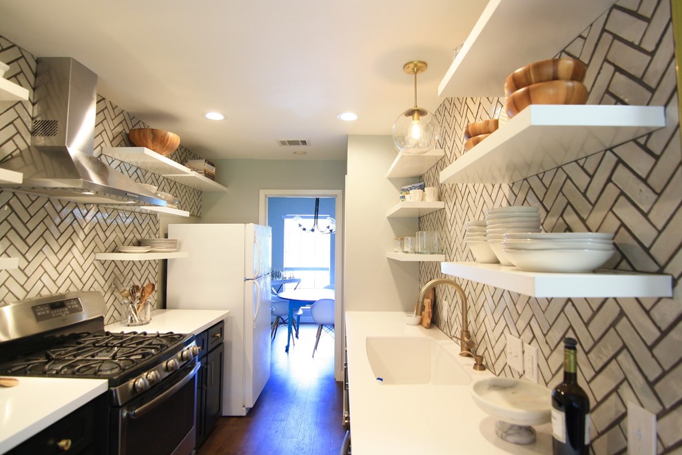 Example of a mid-sized danish galley dark wood floor enclosed kitchen design in Austin with a double-bowl sink, open cabinets, white cabinets, solid surface countertops, white backsplash, ceramic backsplash, black appliances and no island