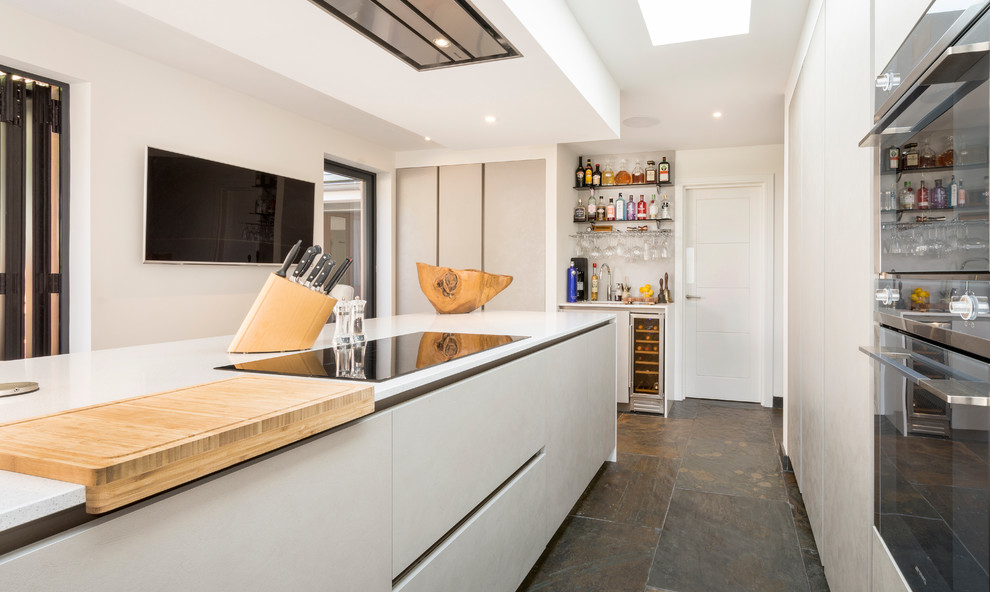 Moderne Küche ohne Insel mit integriertem Waschbecken, flächenbündigen Schrankfronten, Mineralwerkstoff-Arbeitsplatte, Schieferboden und weißer Arbeitsplatte in Devon