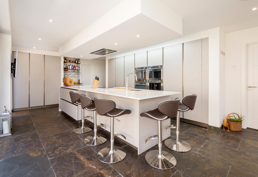 Foto di una cucina moderna con lavello integrato, ante lisce, top in superficie solida, pavimento in ardesia, nessuna isola e top bianco