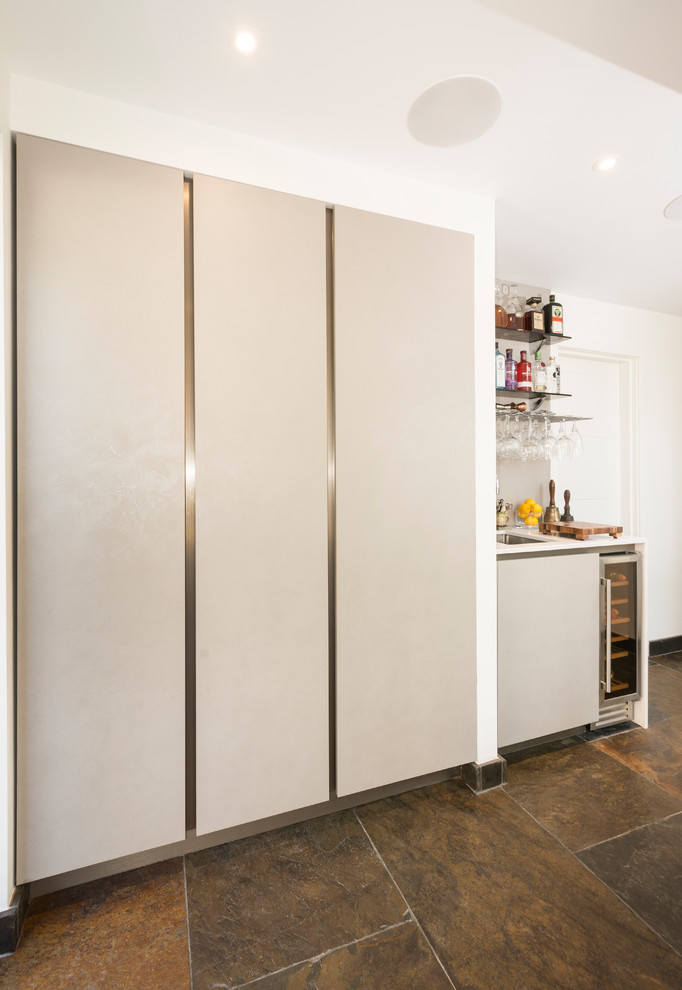 Foto de cocina moderna sin isla con fregadero integrado, armarios con paneles lisos, encimera de acrílico, suelo de pizarra y encimeras blancas