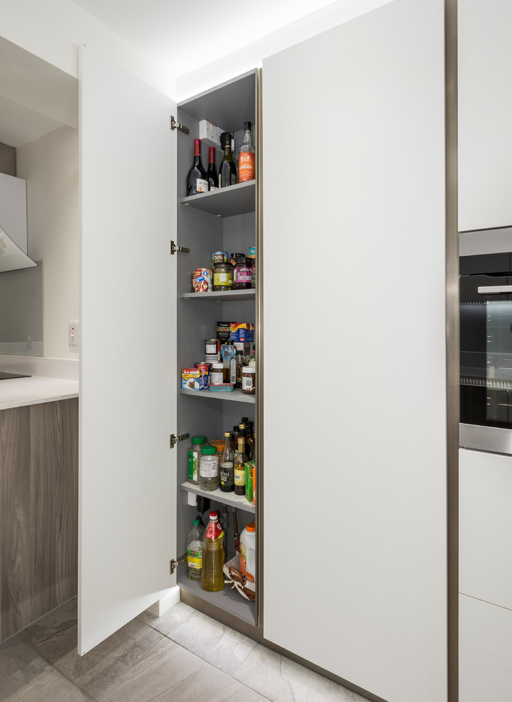 Cette photo montre une petite cuisine parallèle tendance fermée avec un évier intégré, un placard à porte plane, un plan de travail en surface solide et un plan de travail blanc.