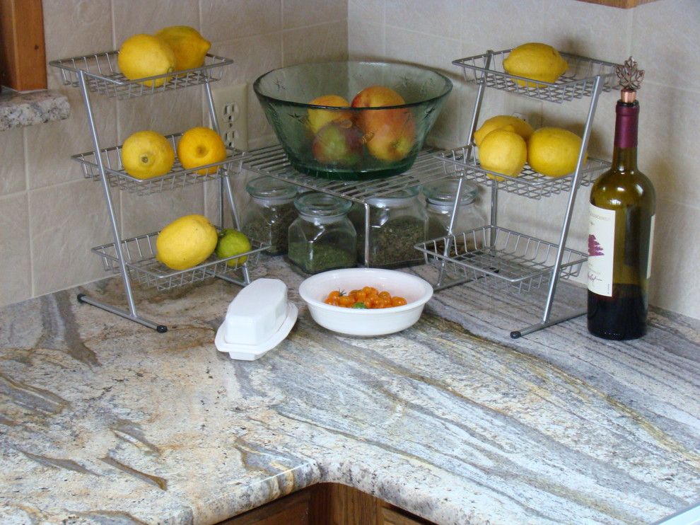 Foto på ett mellanstort amerikanskt l-kök, med en dubbel diskho, luckor med infälld panel, skåp i mellenmörkt trä, granitbänkskiva, vitt stänkskydd, stänkskydd i porslinskakel, rostfria vitvaror och ljust trägolv