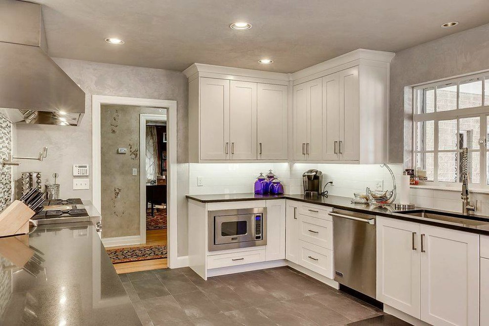 Example of a mid-sized transitional u-shaped ceramic tile and gray floor enclosed kitchen design in Oklahoma City with an undermount sink, shaker cabinets, white cabinets, granite countertops, white backsplash, porcelain backsplash, stainless steel appliances and no island