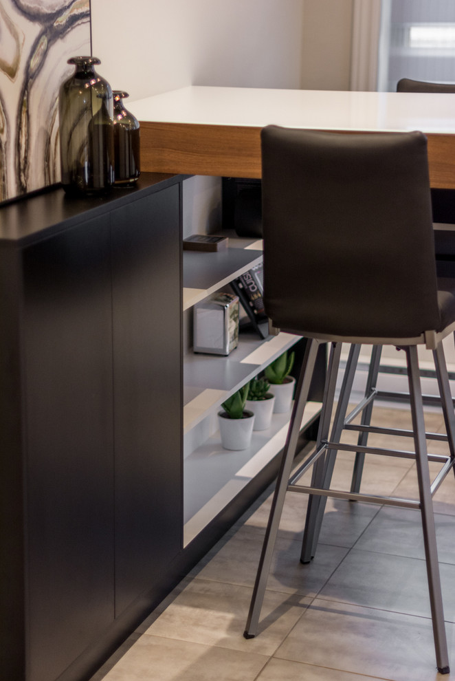 モントリオールにある小さなインダストリアルスタイルのおしゃれなキッチン (フラットパネル扉のキャビネット、黒いキャビネット、ガラスカウンター、白いキッチンパネル、シルバーの調理設備、セラミックタイルの床) の写真