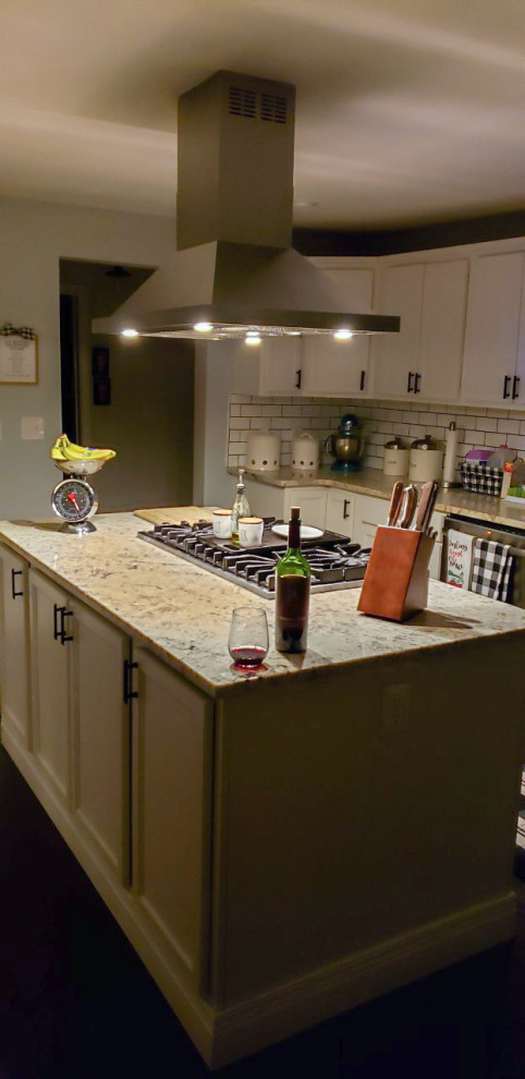 Foto på ett mellanstort brun kök, med granitbänkskiva, stänkskydd i tegel, rostfria vitvaror, en köksö, släta luckor, vita skåp och vitt stänkskydd