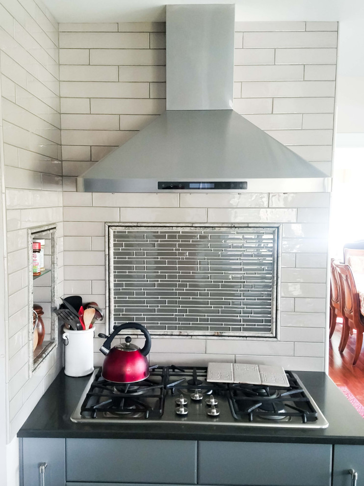 Cette image montre une petite cuisine américaine linéaire avec un plan de travail en onyx, un électroménager en acier inoxydable, un sol en bois brun, un sol marron et plan de travail noir.