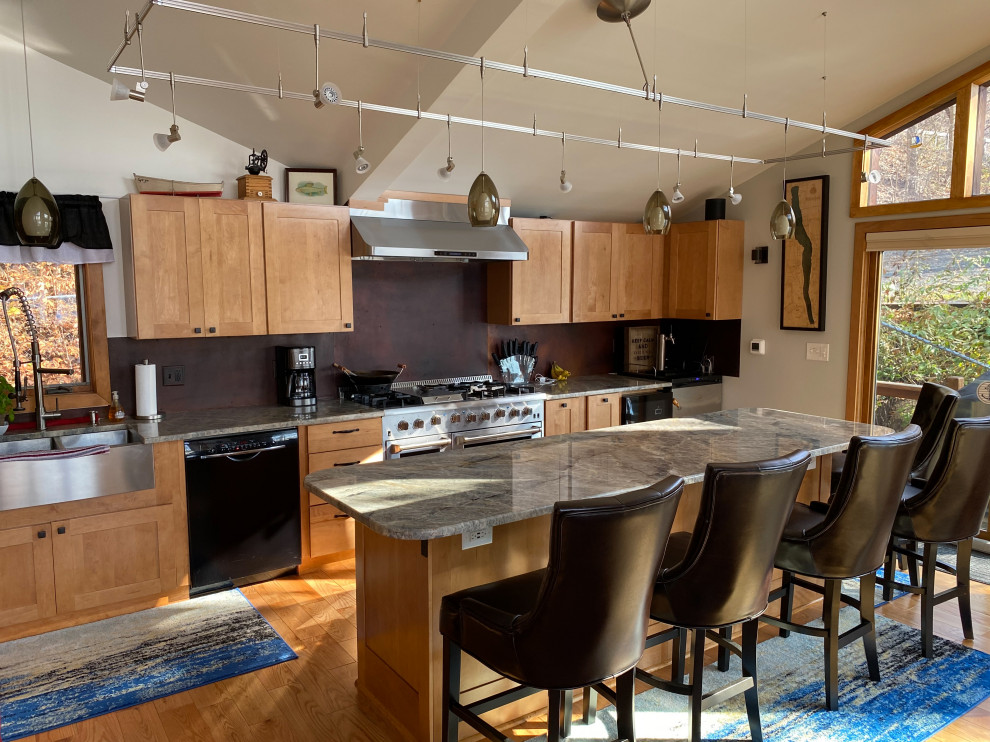 Bild på ett litet funkis grå grått kök, med en dubbel diskho, skåp i shakerstil, skåp i ljust trä, granitbänkskiva, brunt stänkskydd, rostfria vitvaror, ljust trägolv, en köksö och brunt golv