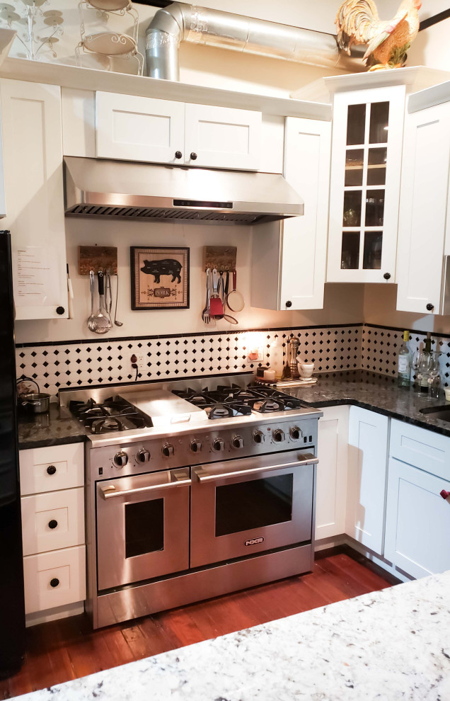 Esempio di una cucina minimalista di medie dimensioni con paraspruzzi con piastrelle in ceramica, elettrodomestici in acciaio inossidabile, pavimento in legno massello medio, pavimento marrone, ante con riquadro incassato, top in granito, paraspruzzi multicolore, top nero e ante bianche