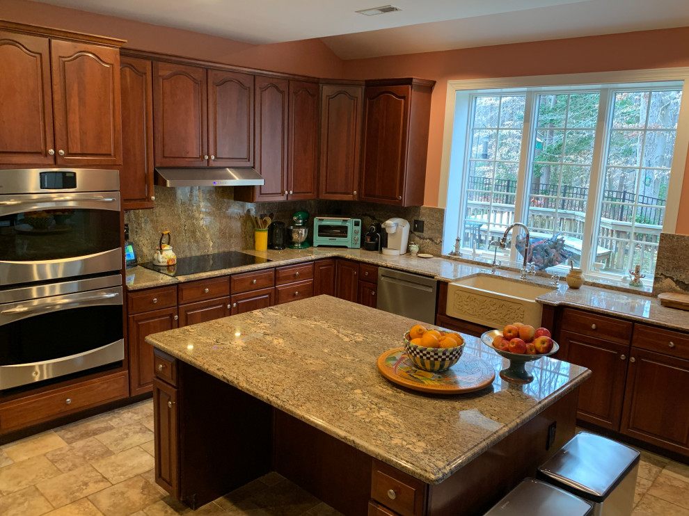 Inredning av ett modernt mellanstort brun brunt kök, med en rustik diskho, luckor med upphöjd panel, skåp i mörkt trä, granitbänkskiva, brunt stänkskydd, rostfria vitvaror, cementgolv, en köksö och beiget golv