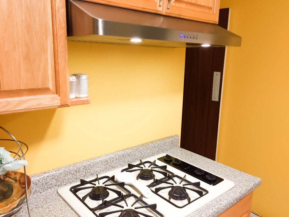 Esempio di una piccola cucina moderna con ante con riquadro incassato, ante in legno scuro, top in granito, paraspruzzi giallo, elettrodomestici in acciaio inossidabile, nessuna isola e top beige
