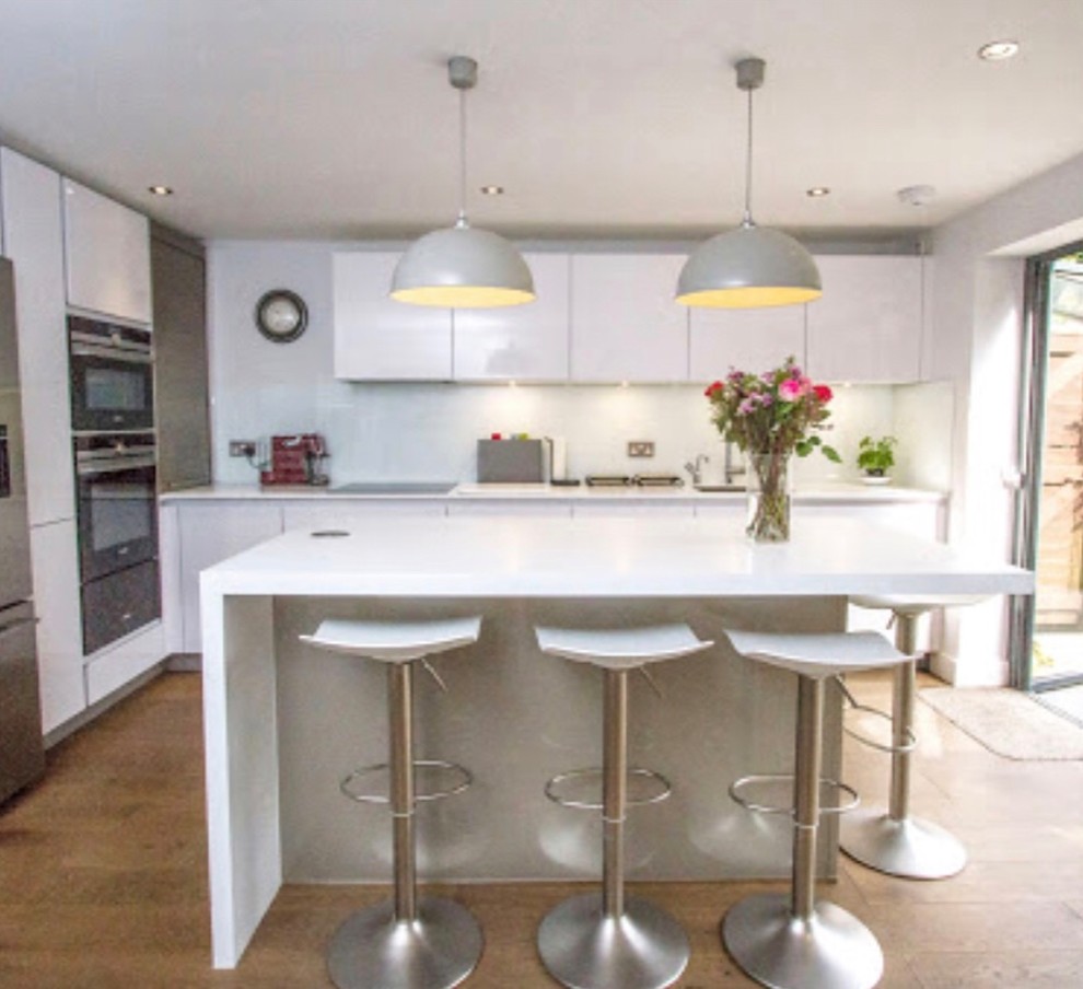 Photo of a medium sized contemporary l-shaped kitchen/diner in London with a built-in sink, flat-panel cabinets, laminate countertops, yellow worktops, beige cabinets and an island.
