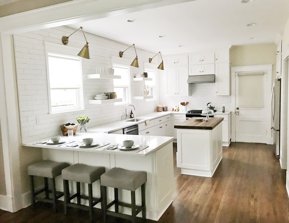 Inspiration for a medium sized contemporary l-shaped kitchen/diner in Nashville with a single-bowl sink, shaker cabinets, white cabinets, engineered stone countertops, white splashback, metro tiled splashback, stainless steel appliances, medium hardwood flooring, an island and brown floors.
