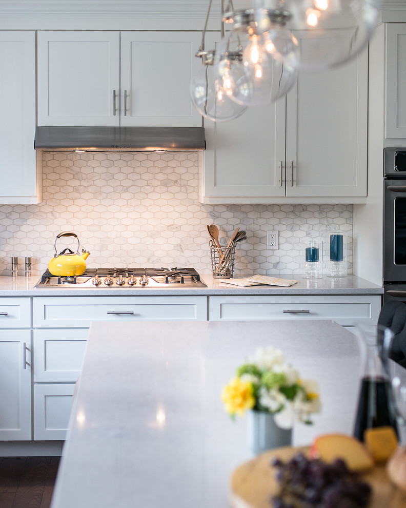 Large transitional l-shaped dark wood floor open concept kitchen photo in New York with a drop-in sink, shaker cabinets, white cabinets, quartzite countertops, white backsplash, mosaic tile backsplash, stainless steel appliances and an island