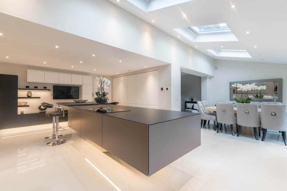 Eat-in kitchen - mid-sized contemporary l-shaped white floor eat-in kitchen idea in Essex with flat-panel cabinets, gray cabinets, an island and paneled appliances